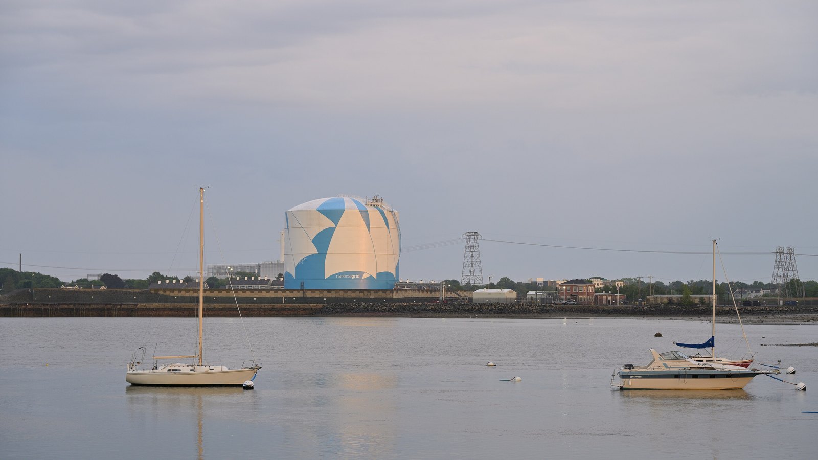 A large natural gas storage tank beside a river with boats
