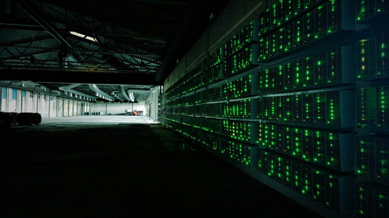 Rows of bitcoin mining machines with green indicator lights in a mining facility